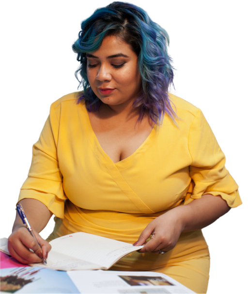 Eine Frau im gelben Kleid mit blauen Haaren schreibt in ein Notizbuch.