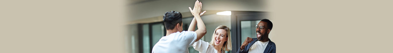Zwei Leute feiern mit einem High Five, während eine dritte Person zuschaut